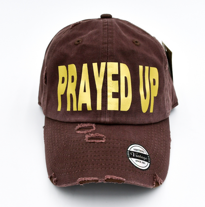 Brown cap with 'PRAYED UP' in yellow on a white background